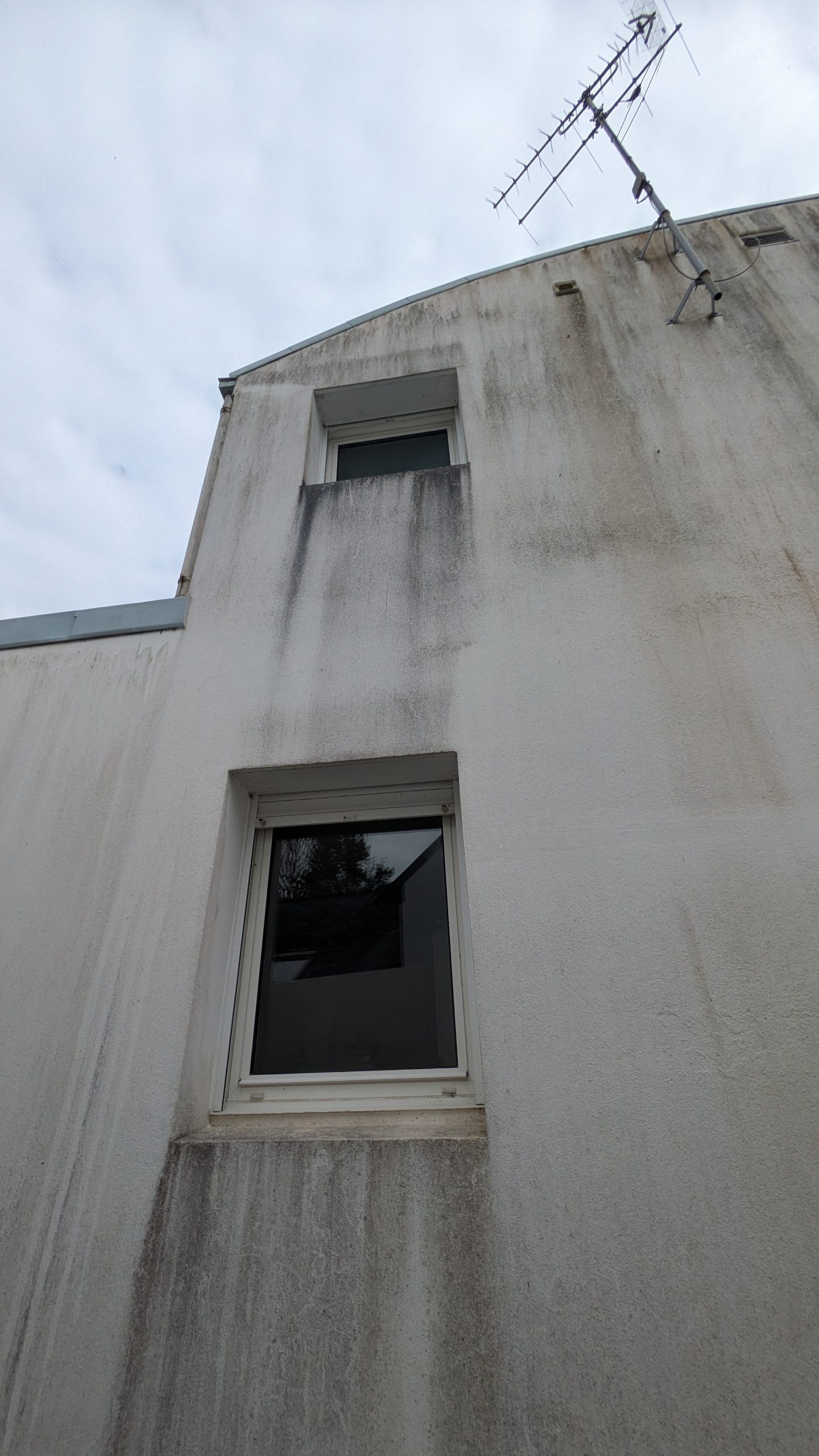 Coulures noires sous les fenêtres d’une façade exposée à l’humidité